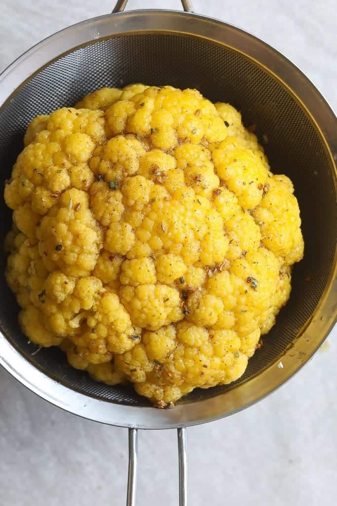 whole cauliflower draining in a colander