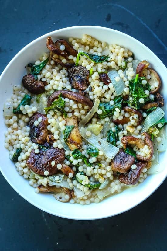 Creamy Israeli couscous with mushrooms and kale in a bowl