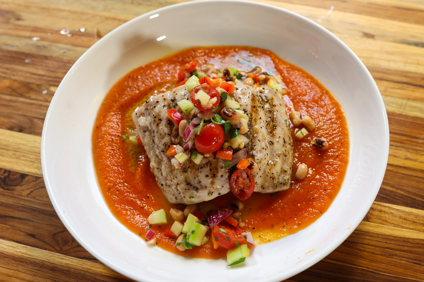 grilled mahi mahi on top of red papaya sauce and topped with blackeyed pea salad