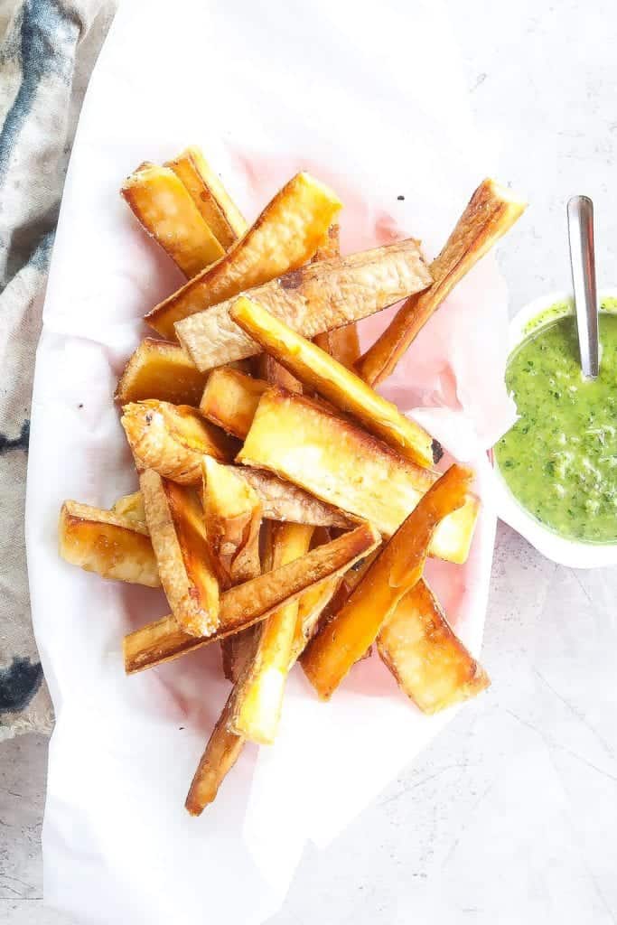 yuca fries with green dipping sauce on a platter