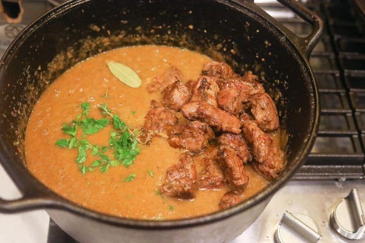 beef and herbs cooking in pot with soup