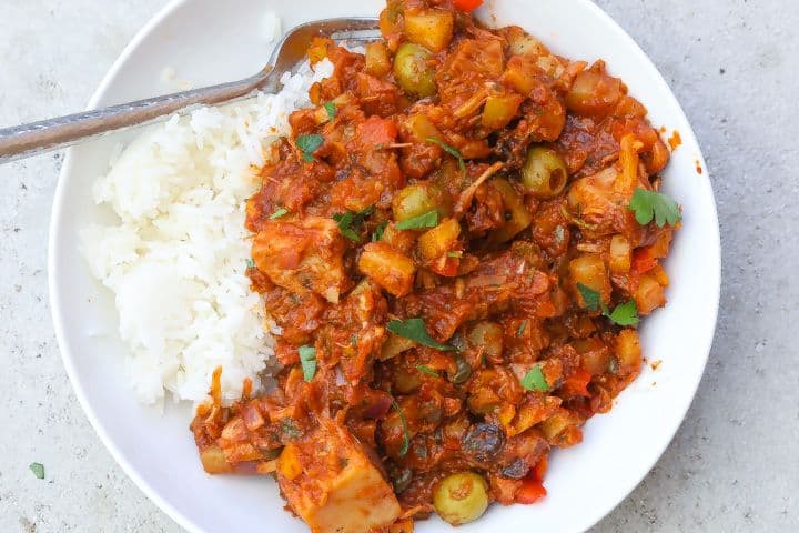 cuban picadillo in a white bowl with rice, fried eggs, and peppers.