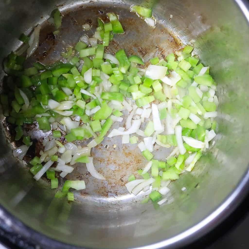 onions and peppers sauteing in pan