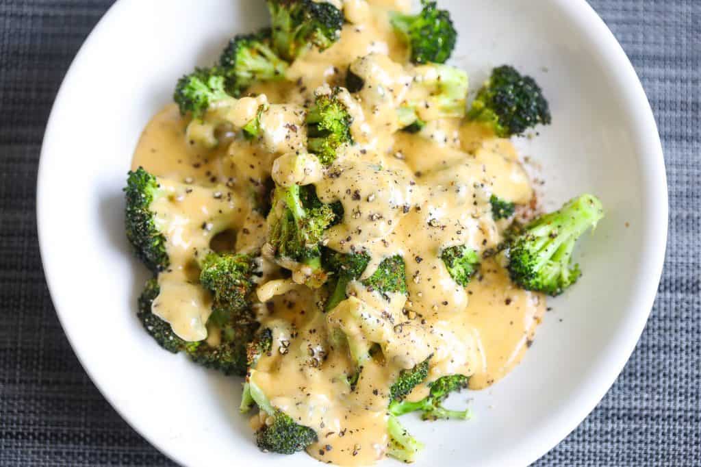 broccoli topped with cheese sauce on white plate