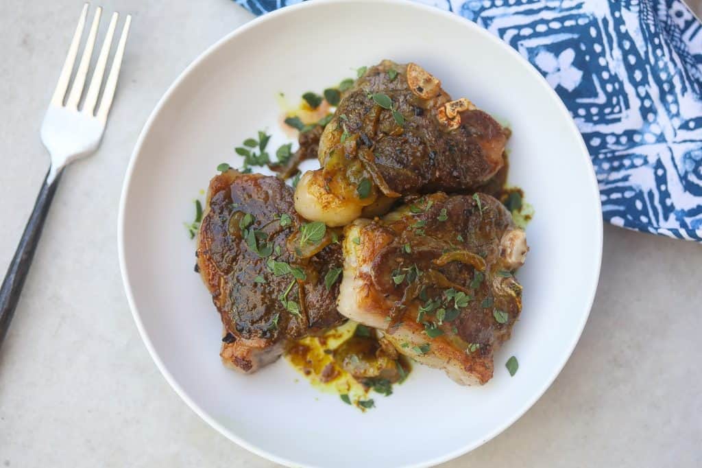 lamb chops on a white plate with spinach and grains