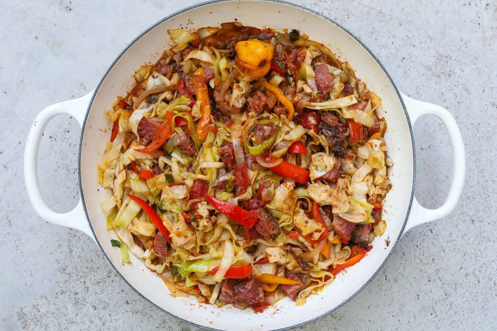 cabbage with corned beef brisket and peppers on a white plate.