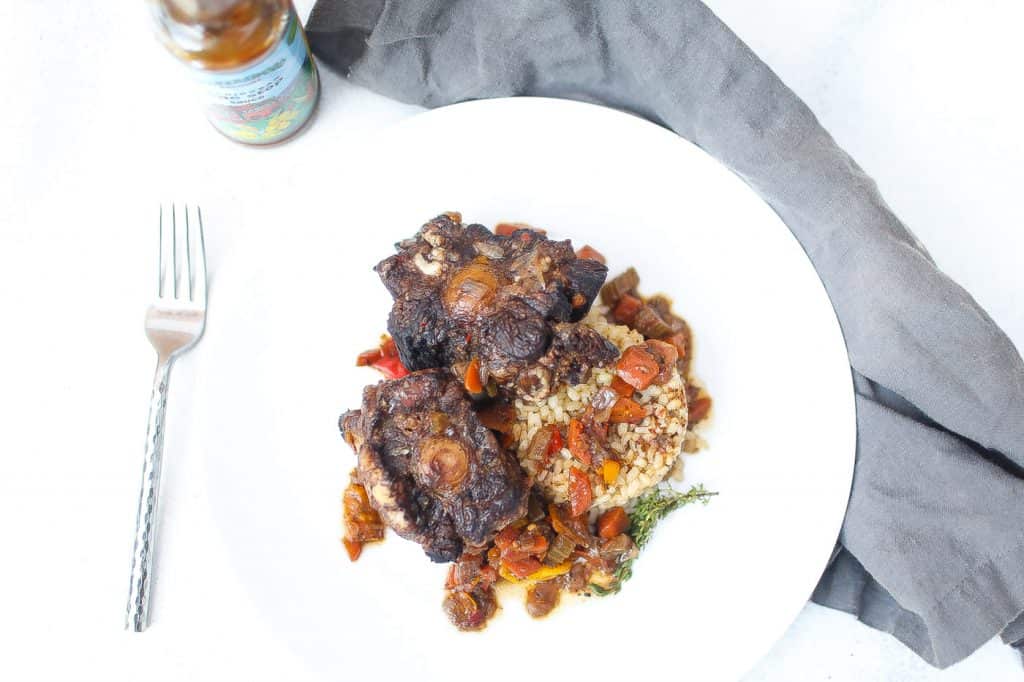 jamaica oxtail on white plate with brown rice