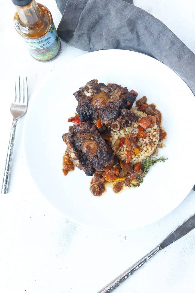 jamaica oxtail on white plate with brown rice