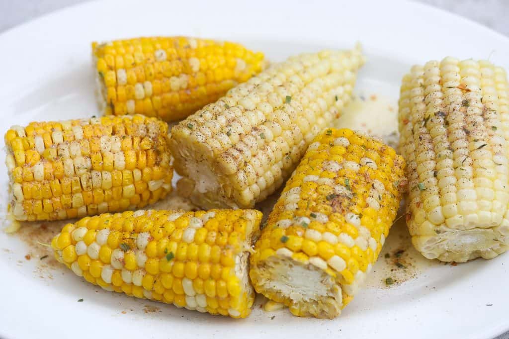 corn on the cob halves on a white oval platter