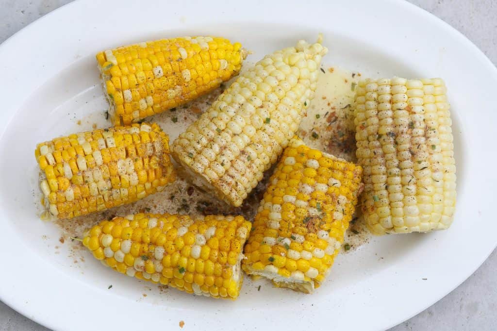 corn on the cob halves on a white oval platter