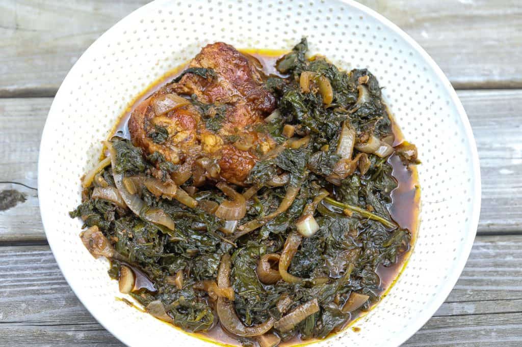 mustard greens with onions and turkey in a white bowl