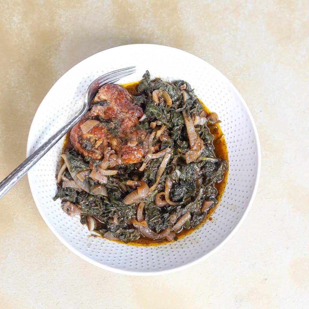 mustard greens with onions and turkey in a white bowl