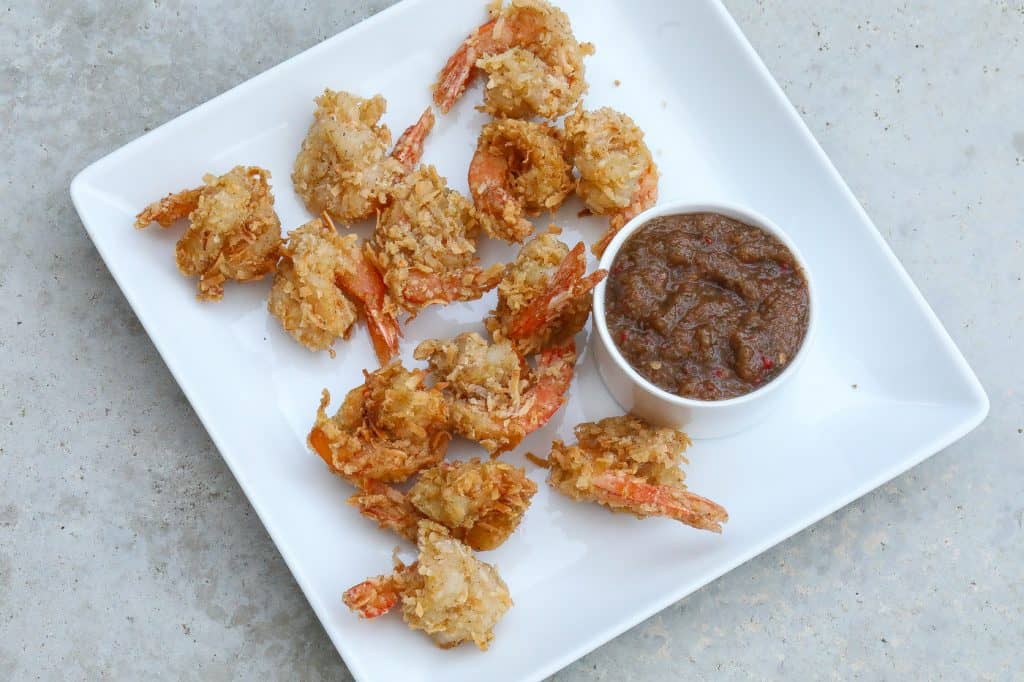 coconut shrimp on white plate with sauce