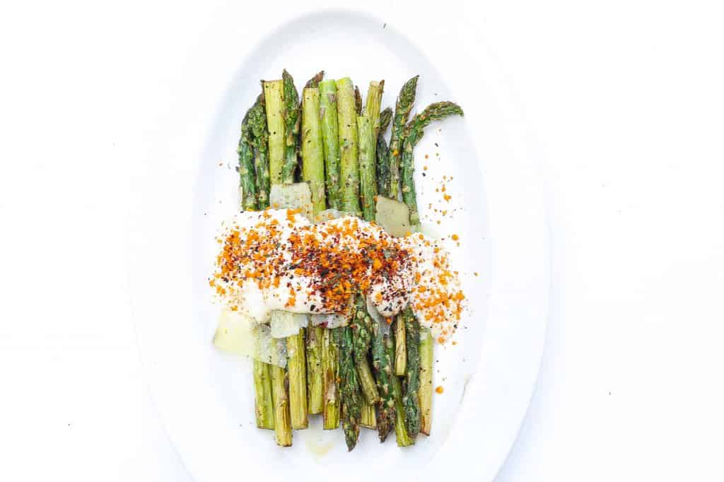 asparagus on a white plate topped with cheese sauce