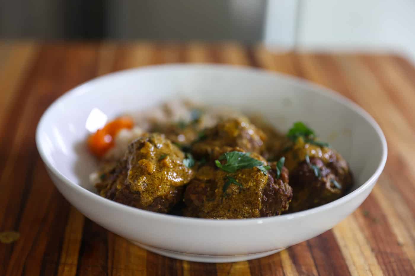 meatballs in bowl with rice topped with gravy