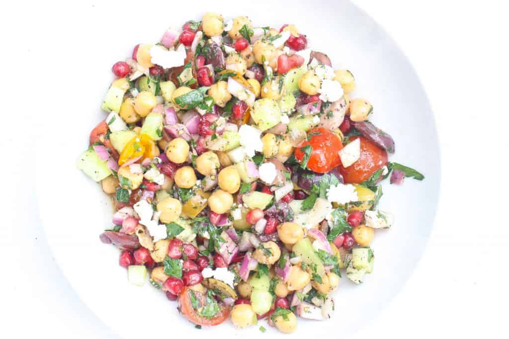 chickpea salad with pomegranate seeds in white bowl