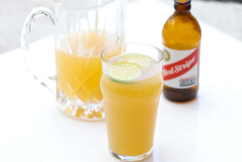 glass of beer flanked by a pitcher and bottle of beer