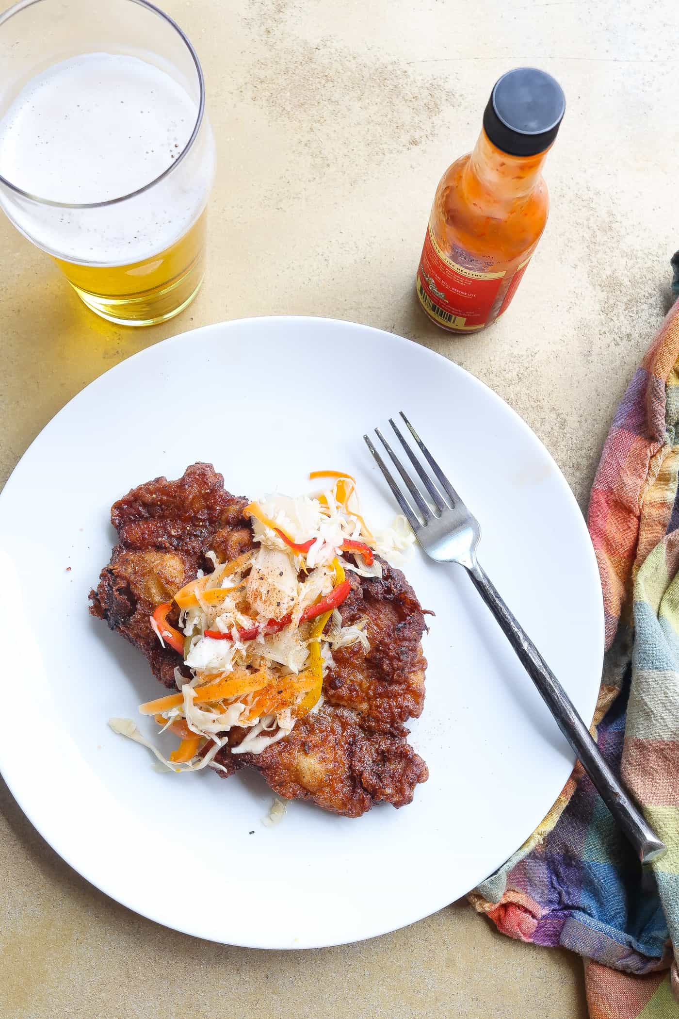 fried pork steak on white plate topped with slaw