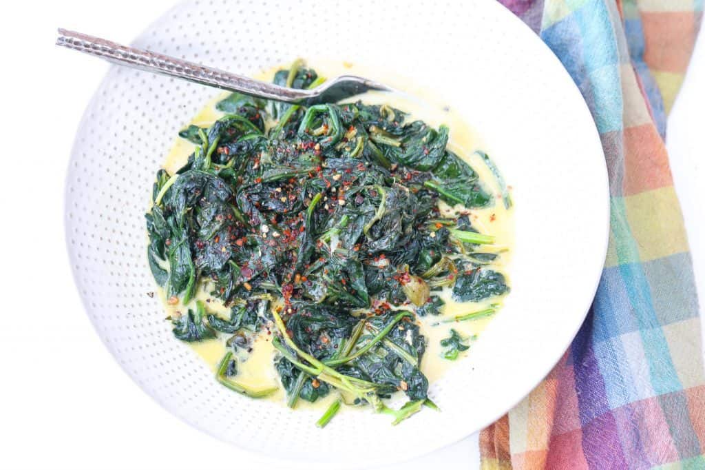 sauteed spinach in a white bowl with creamy sauce