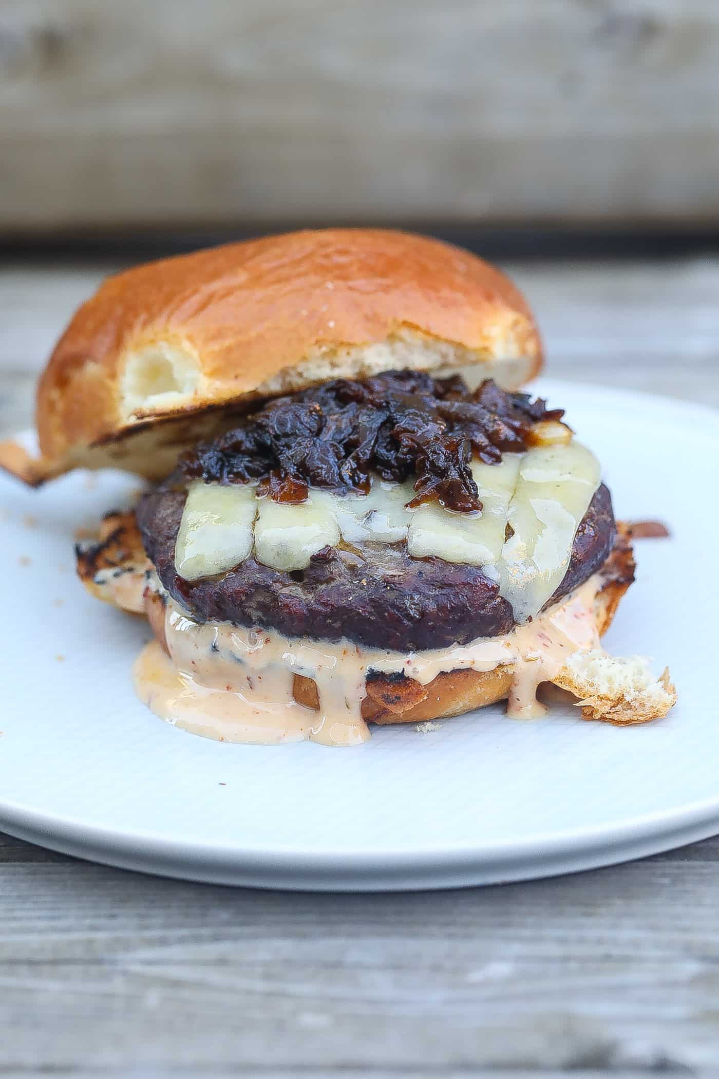 smoked burger with melted cheese, sauce, and caramelized onions
