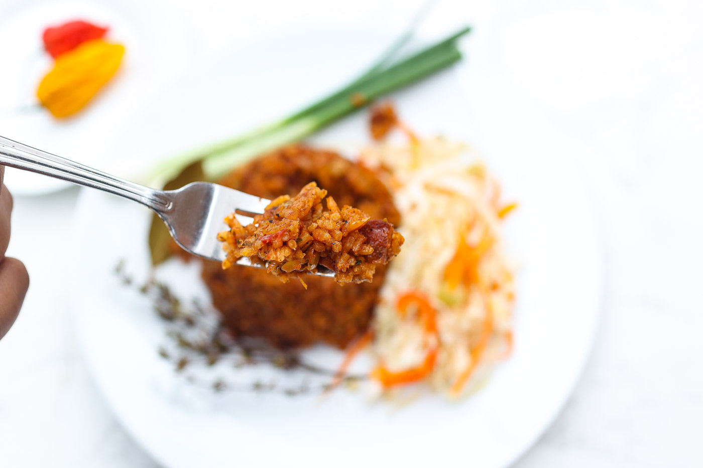 red rice on white plate with green onions and haitian pikliz