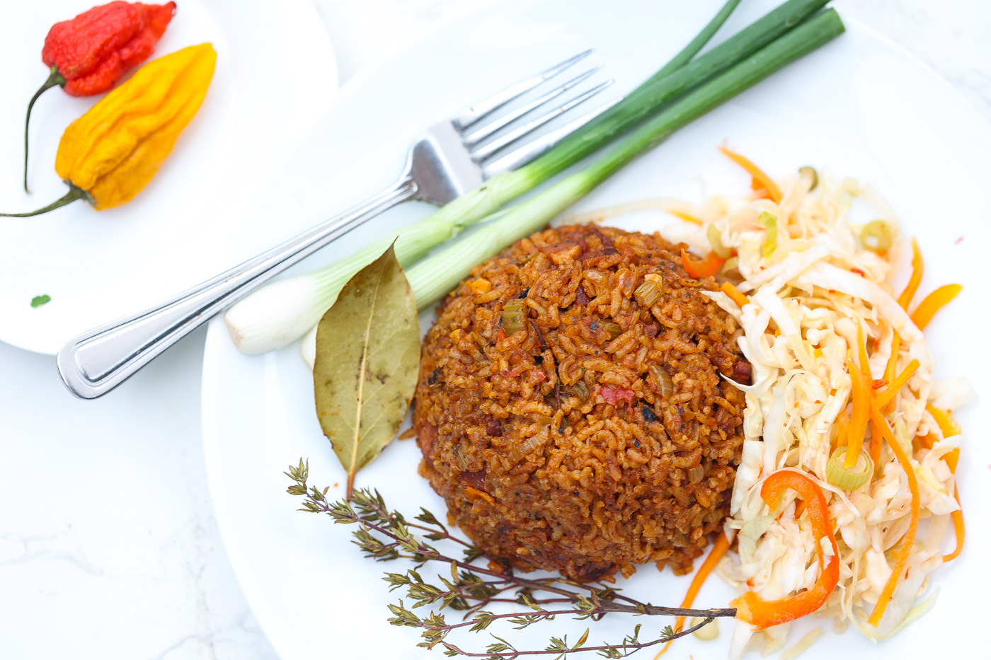 red rice on white plate with green onions and haitian pikliz