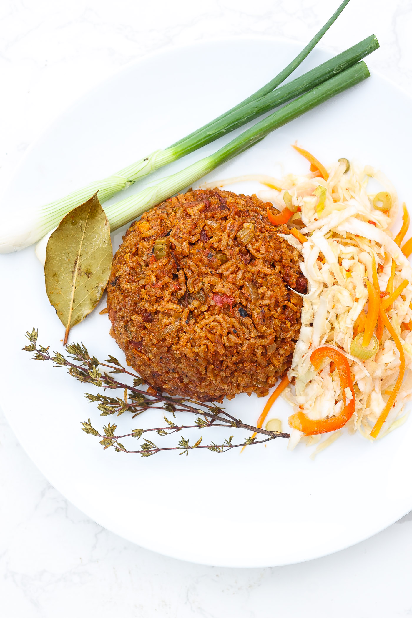 red rice on white plate with green onions and haitian pikliz