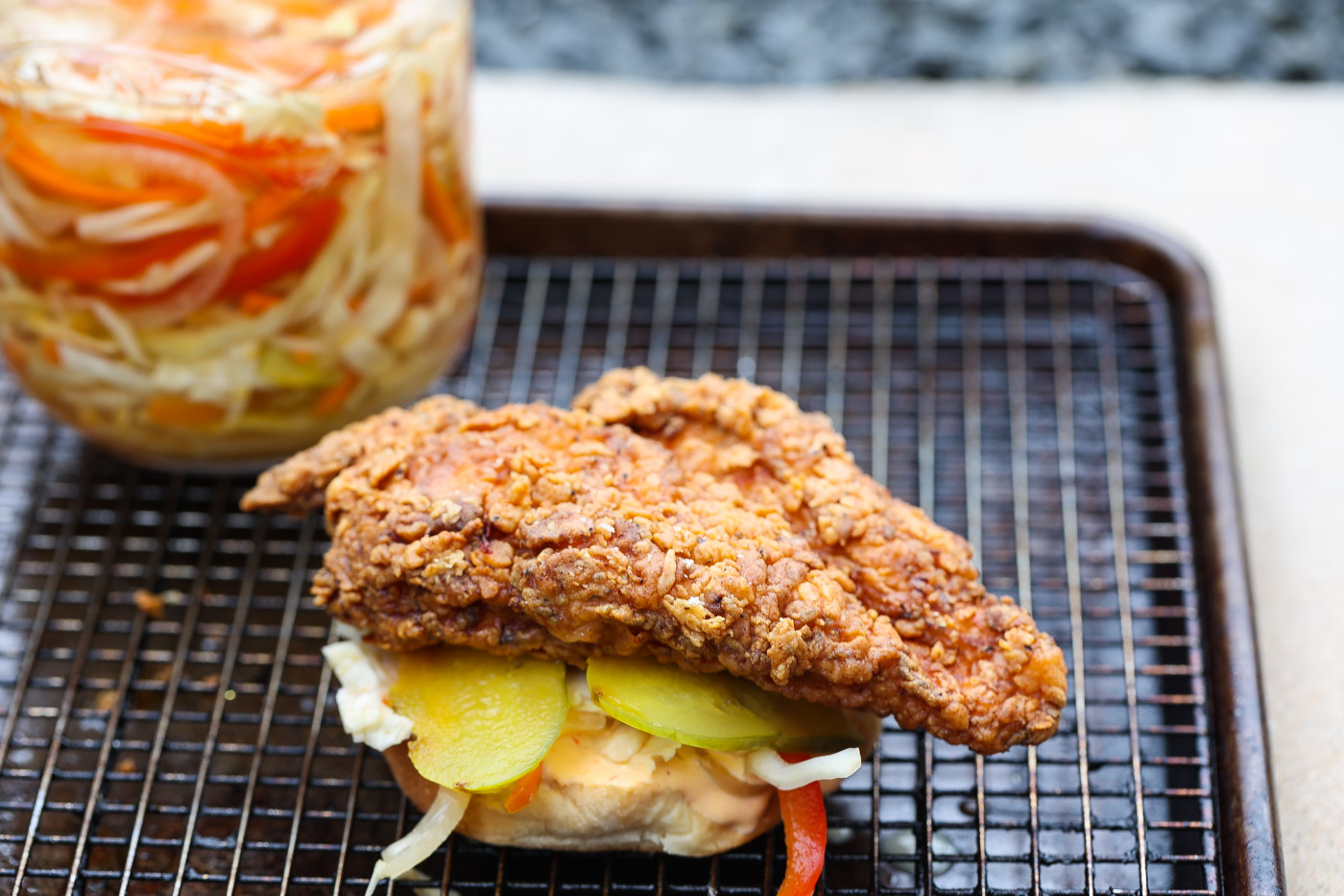 fried chicken sandwich on wire rack lined baking sheet