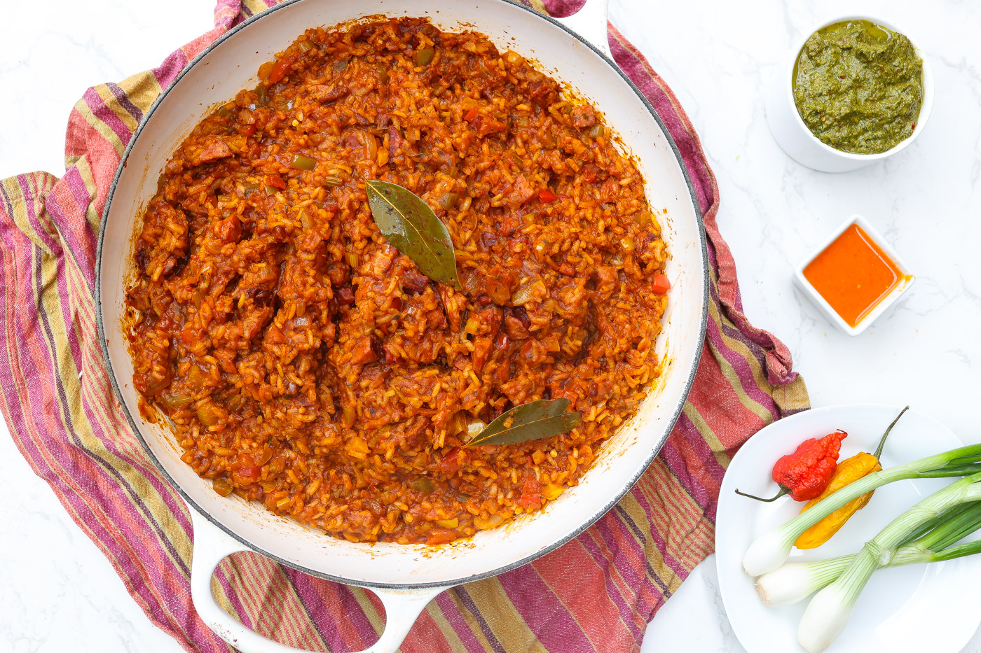 red rice on white plate with green onions and haitian pikliz