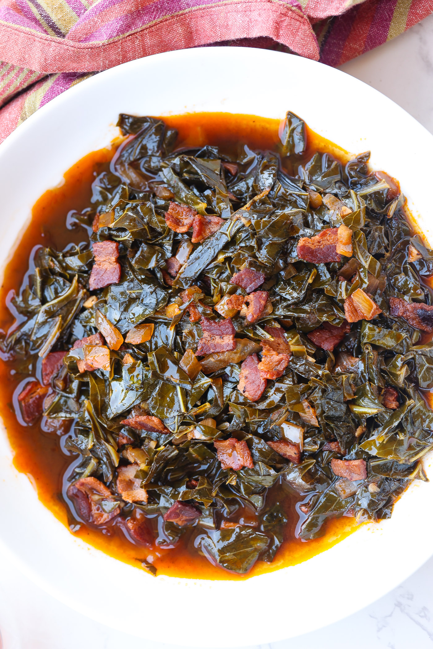 braised collard greens with bacon in a white bowl
