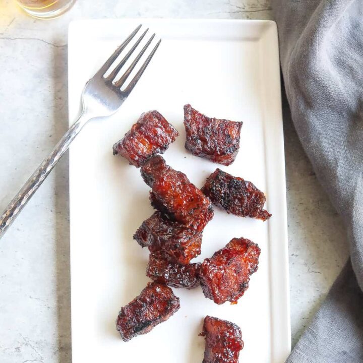 smoked pork belly burnt ends on a white plate