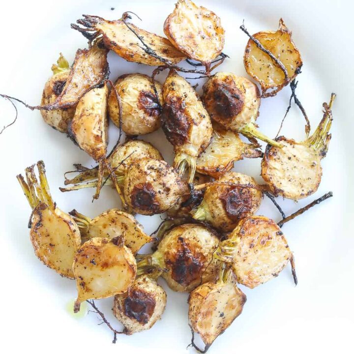 roasted turnips halved and on a white plate.