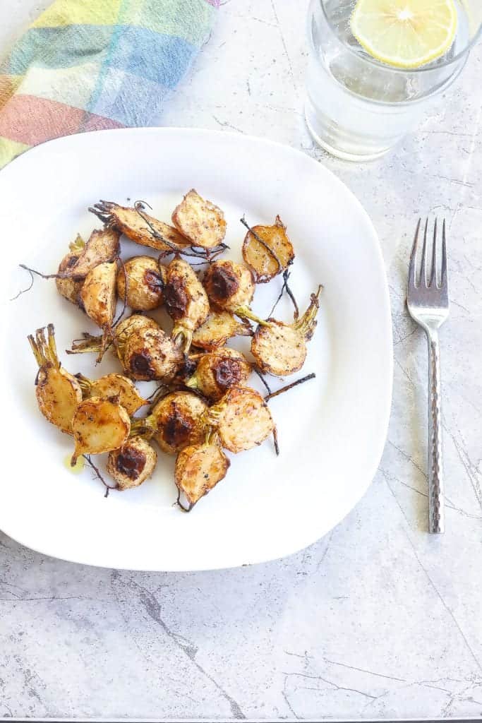 roasted turnips halved and on a white plate.