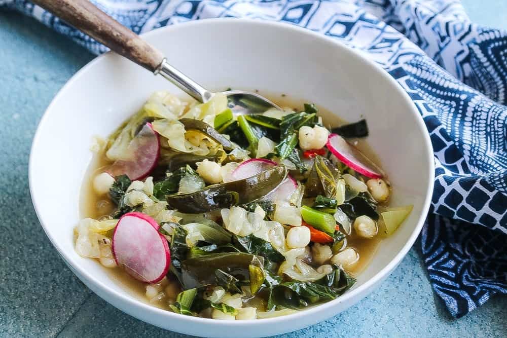 vegan cabbage poblano pozole with collard greens in a bowl