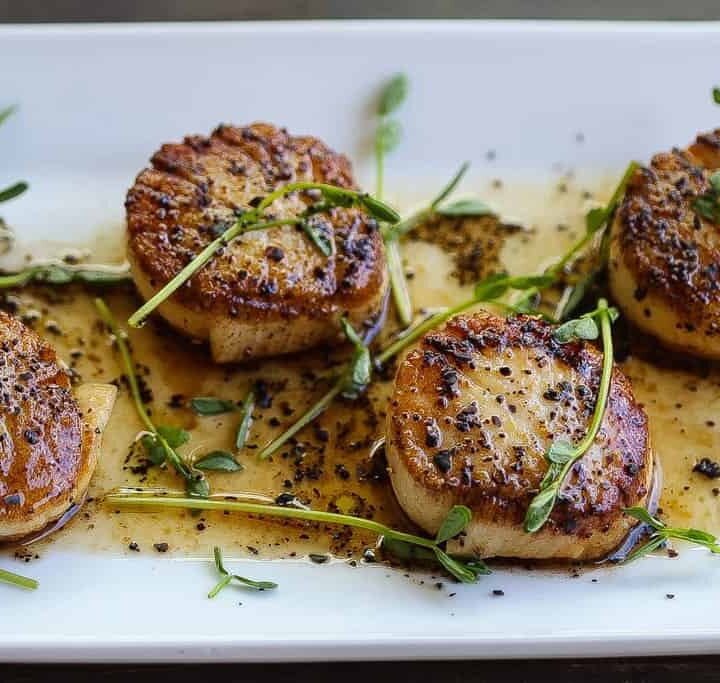 pan-seared scallops on plate topped with herbs and coffee vinaigrette