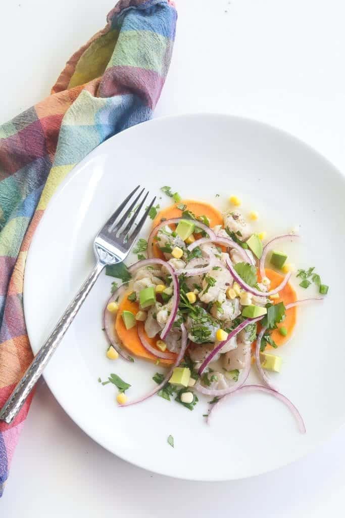 peruvian ceviche on a white plate with sweet potatoes and corn