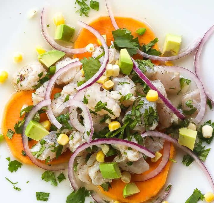 peruvian ceviche on a white plate with sweet potatoes and corn