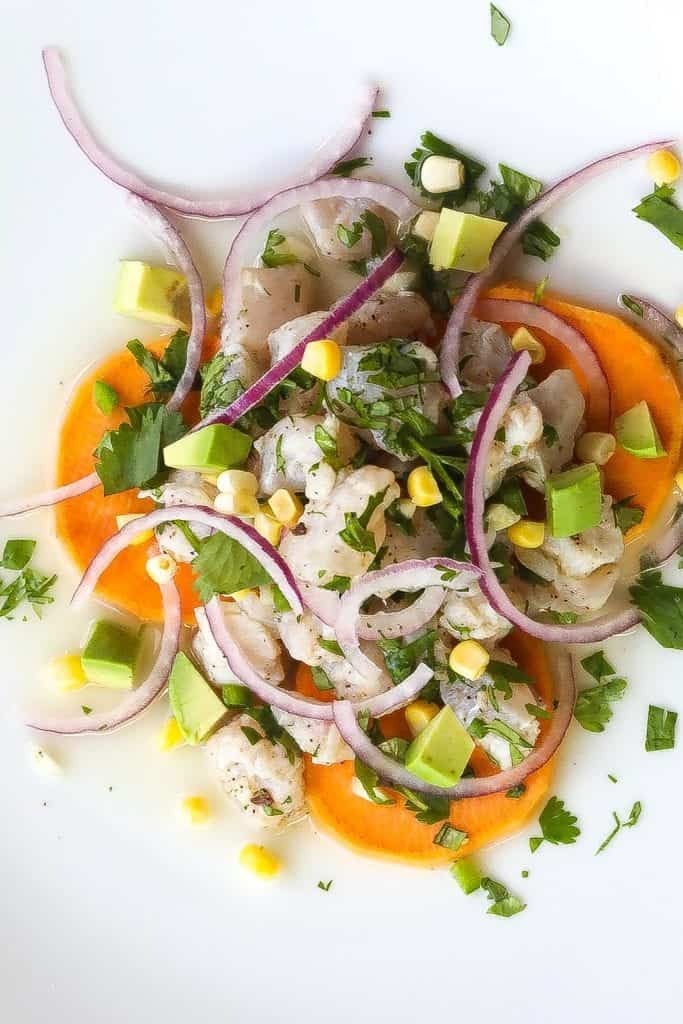 peruvian ceviche on a white plate with sweet potatoes and corn