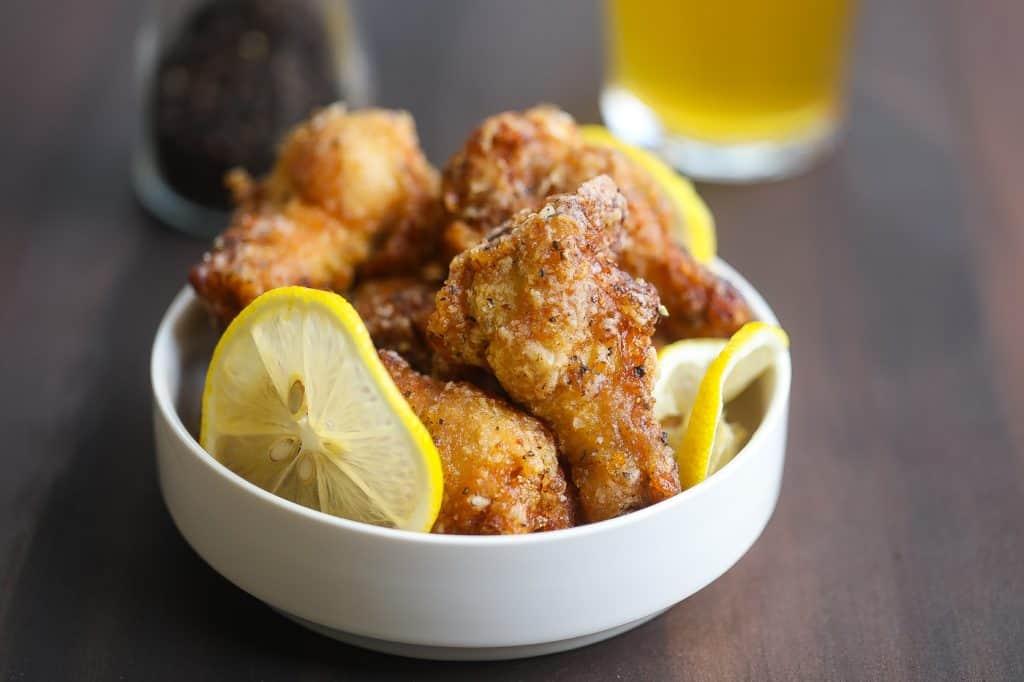 lemon pepper wings in a white bowl with lemons