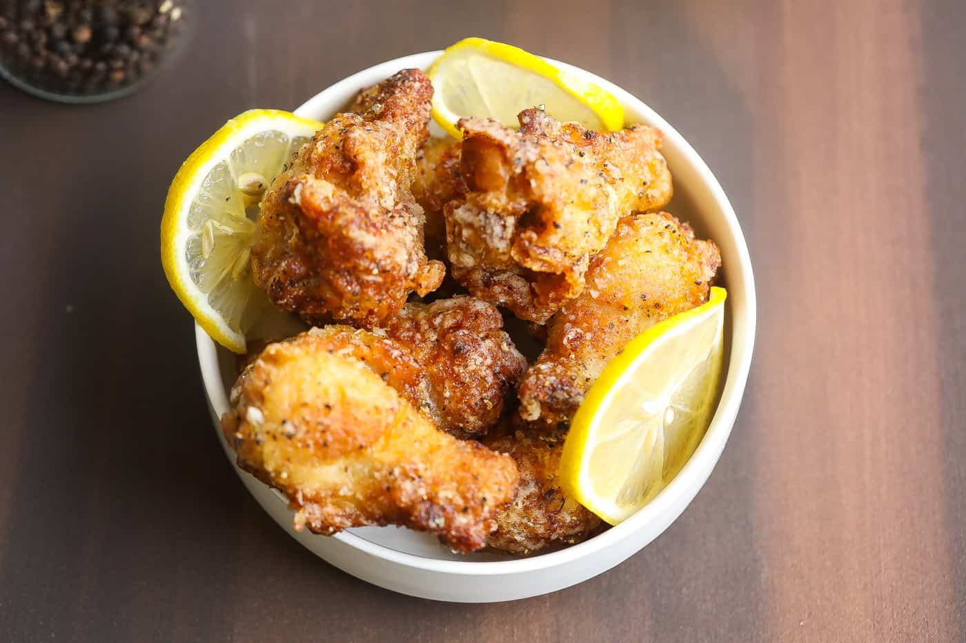 lemon pepper wings in a white bowl with lemons