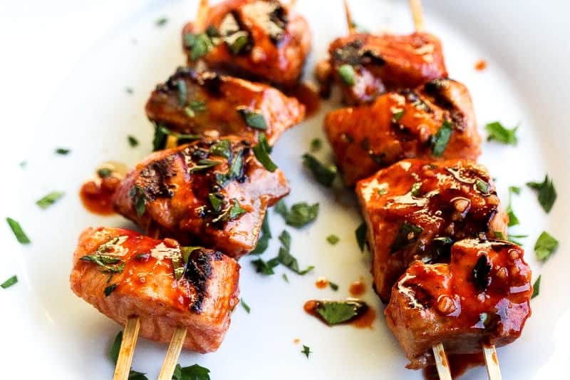 peruvian fish kebabs on white plate topped with cilantro