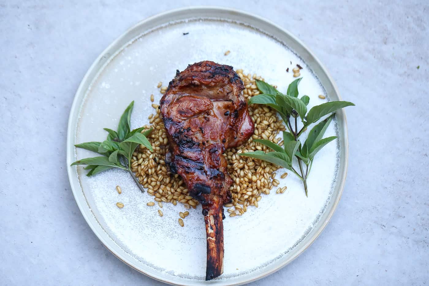 grilled veal chops on a white plate with grains