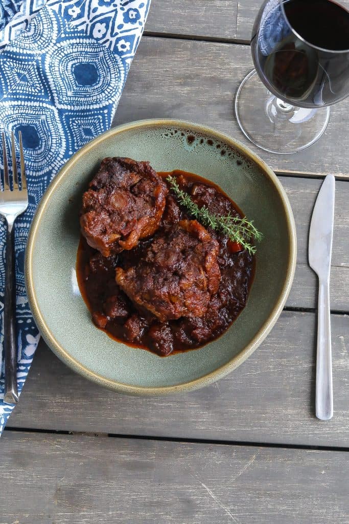 beef oxtails and red sauce in green bowl