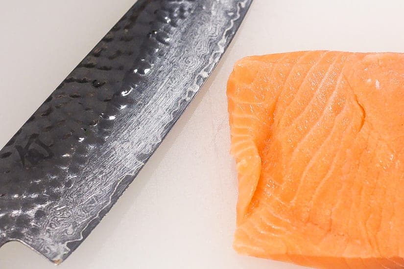sushi grade salmon with sharp knife
