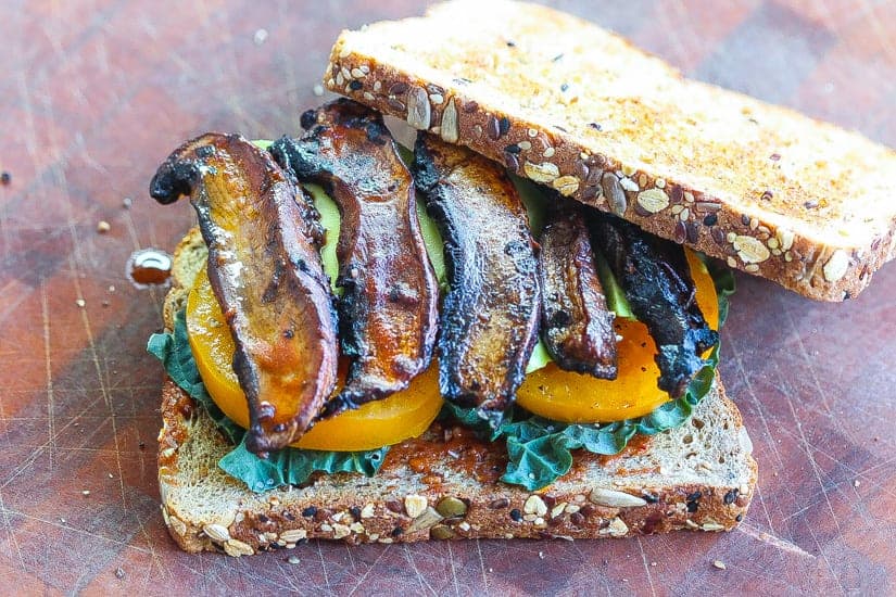 Vegan BLT Sandwich with mushroom slices with yellow tomatoes and black kale on two slices of bread