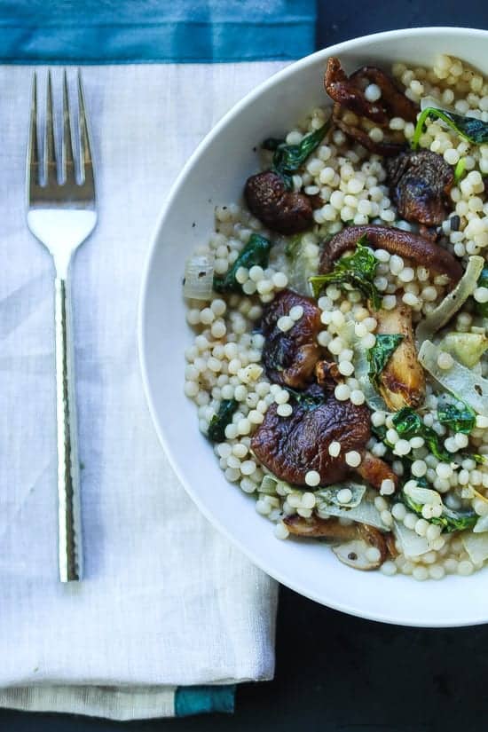 Creamy Israeli couscous with mushrooms and kale in a bowl