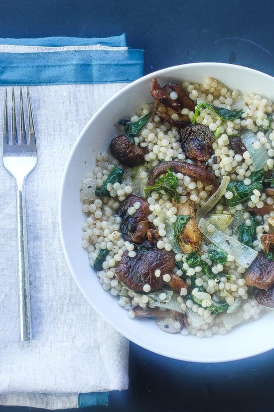 Creamy Israeli couscous with mushrooms and kale in a bowl