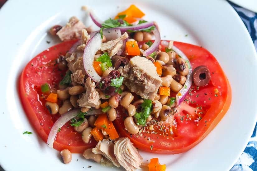 tuna tomato salad with peas, onions, and cilantro on a white plate