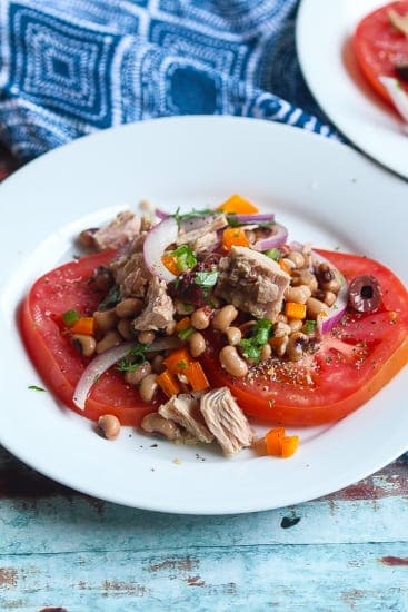 tuna tomato salad with peas, onions, and cilantro on a white plate