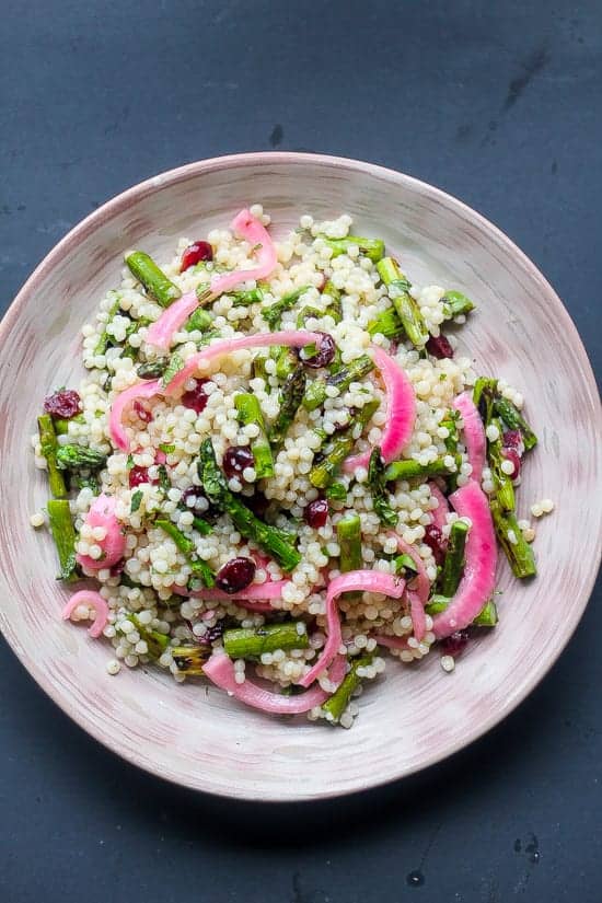 citrus israeli couscous with asparagus and cranberries on a plate
